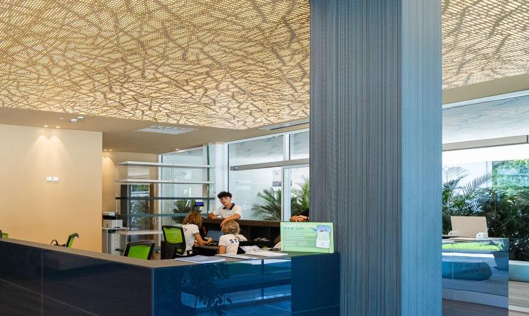 Modern office with perforated ceiling, blue furniture, and welcoming atmosphere.