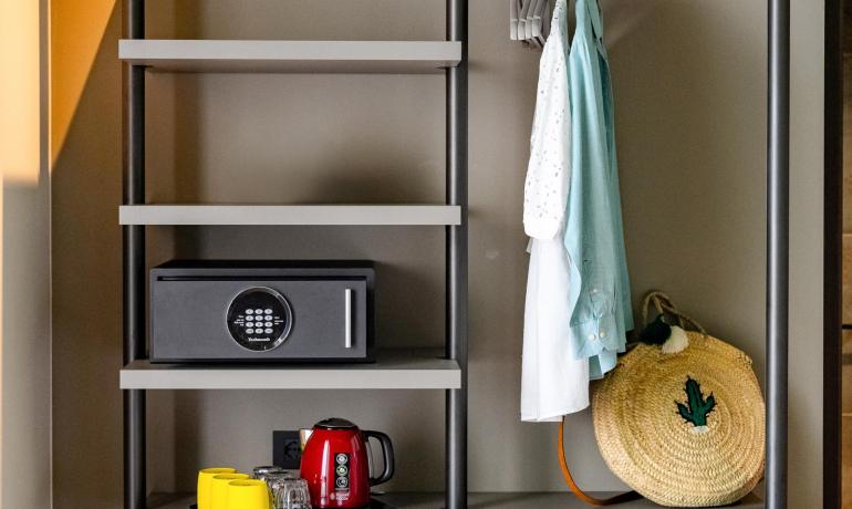 Modern closet with safe, red kettle, and hanging clothes, cozy atmosphere.