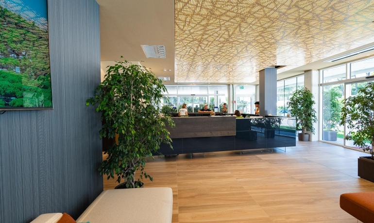 Elegante hall moderna con piante, soffitto artistico e luce naturale.