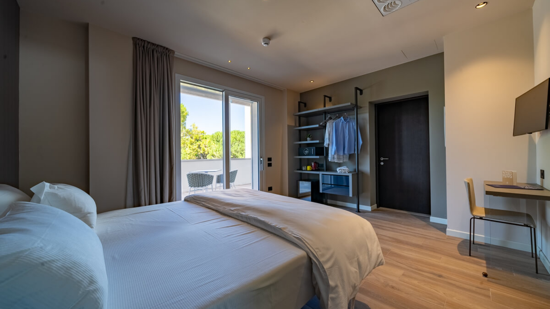 Modern room with balcony, double bed, and desk.