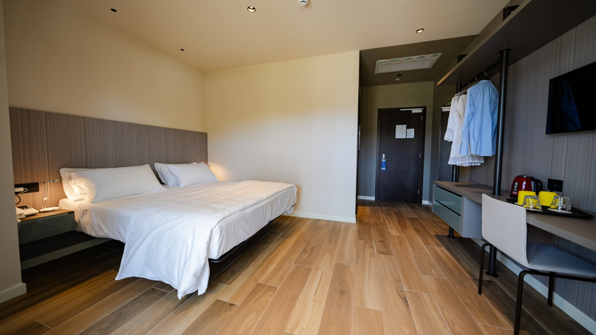 Modern room with double bed and wooden floor.