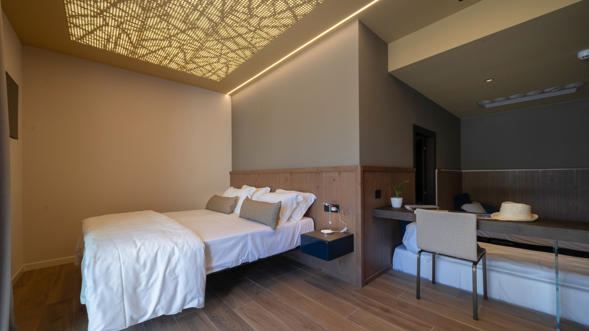 Modernes Zimmer mit Doppelbett und dekorativer Deckenbeleuchtung.
