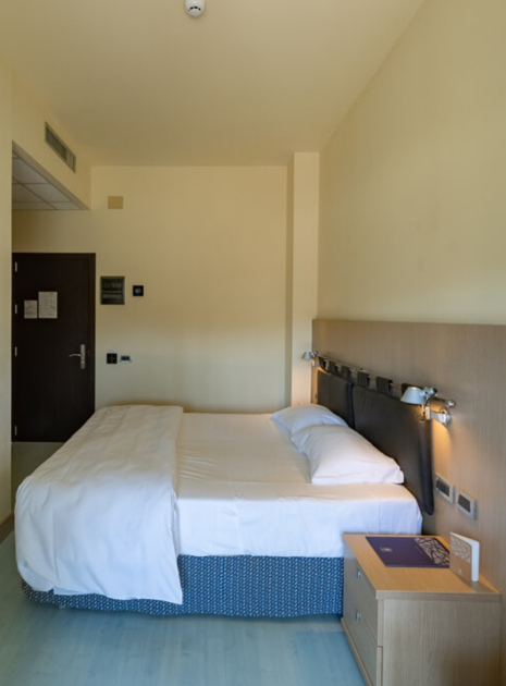 Modern hotel room with a double bed and kettle.