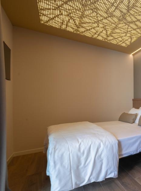 Modern room with double bed and decorative ceiling lighting.