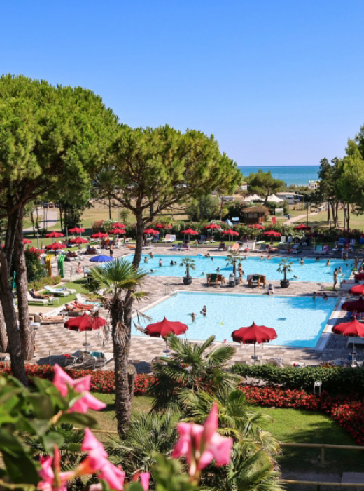 Piscina all'aperto con ombrelloni rossi vicino al mare.