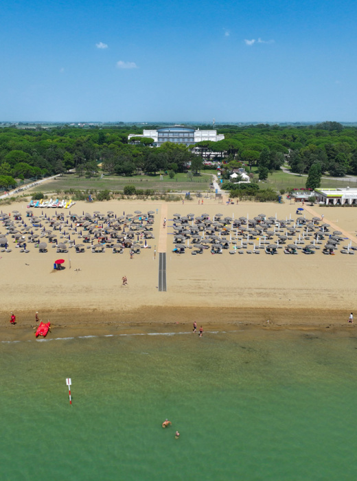 Vista aerea di spiaggia, piscina e campo da tennis.