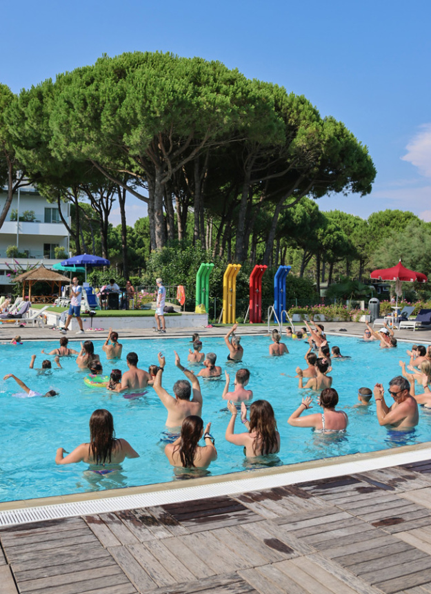 Lively pool with people doing water aerobics under the summer sun.