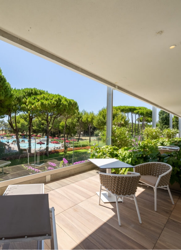 Terrace overlooking pool and trees, modern furniture.